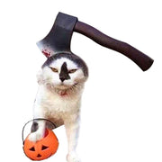 Cat wearing a Halloween pet headdress hat with a fake bloody axe and holding a pumpkin bucket for trick-or-treating.
